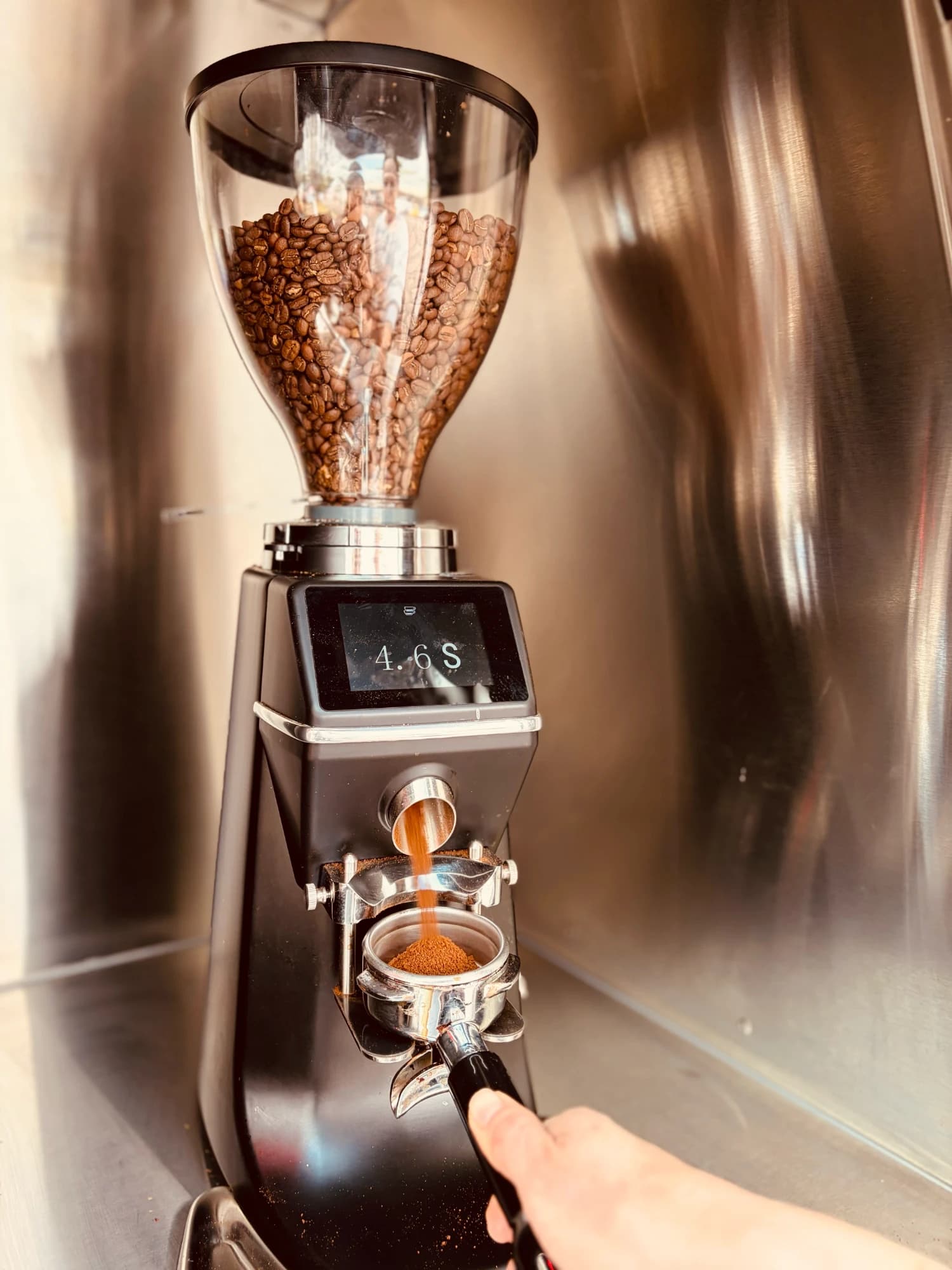 Coffee grinder dosing fresh grounds into a portafilter